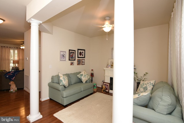 living room with decorative columns, dark wood-type flooring, and ceiling fan