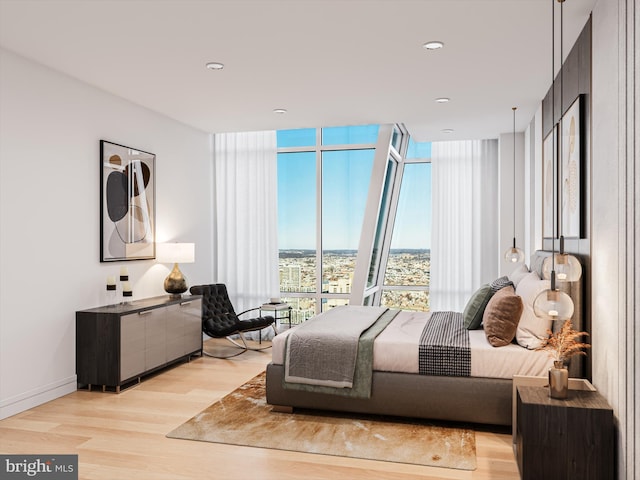 bedroom with floor to ceiling windows and light hardwood / wood-style flooring