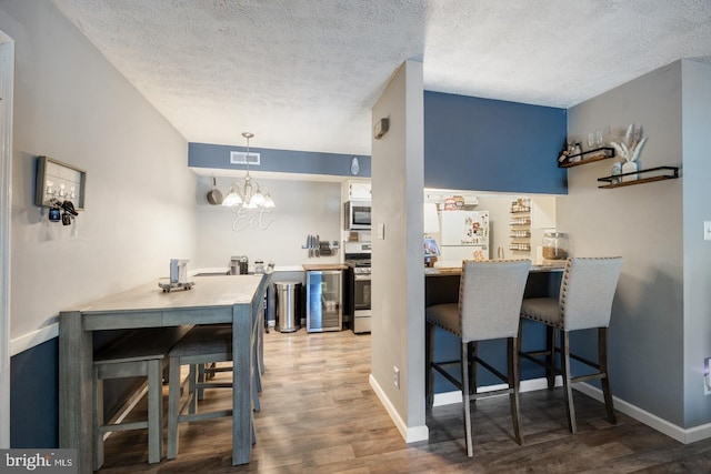 kitchen featuring a kitchen bar, hardwood / wood-style flooring, a textured ceiling, and appliances with stainless steel finishes