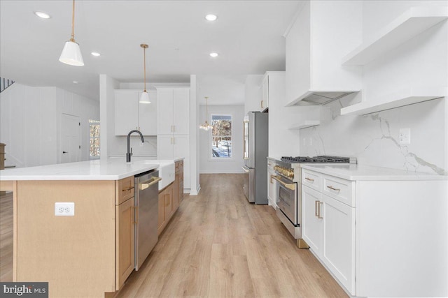 kitchen with pendant lighting, stainless steel appliances, tasteful backsplash, an island with sink, and white cabinets