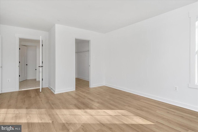 unfurnished bedroom with a walk in closet, light hardwood / wood-style floors, and a closet