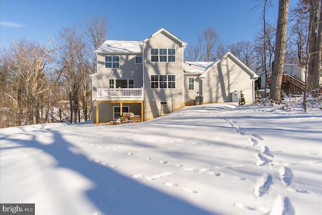 snow covered property with central AC unit and a balcony