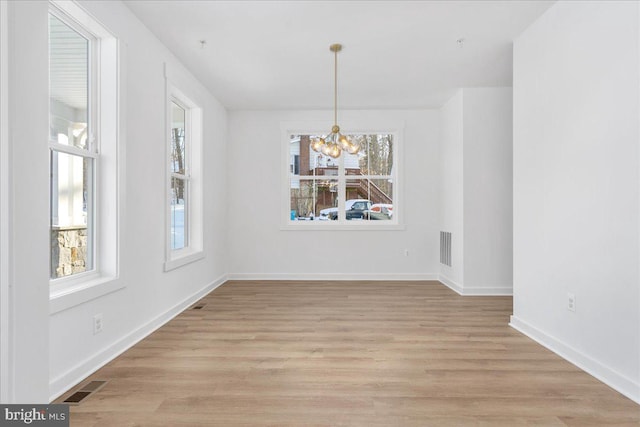 unfurnished dining area featuring a notable chandelier and light hardwood / wood-style flooring