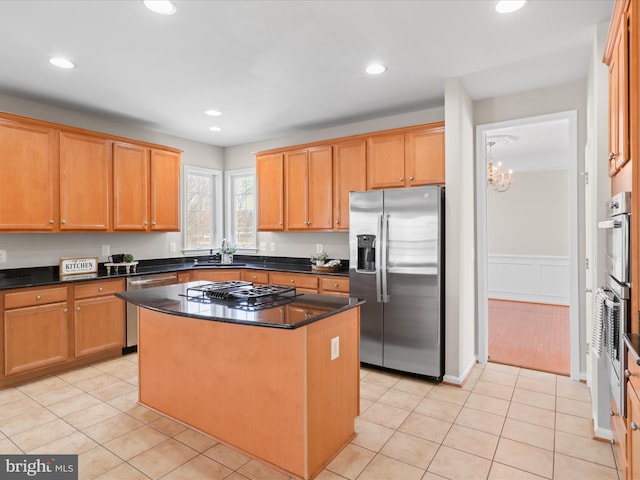 kitchen featuring light tile patterned flooring, stainless steel appliances, dark stone counters, and a kitchen island