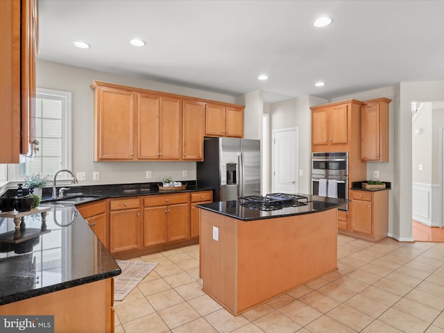 kitchen with stainless steel appliances, sink, a kitchen island, and dark stone counters