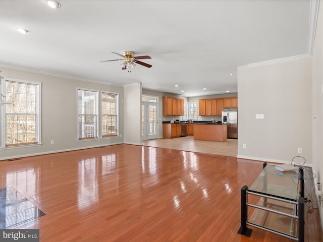 living room featuring ornamental molding, a wealth of natural light, and light hardwood / wood-style floors