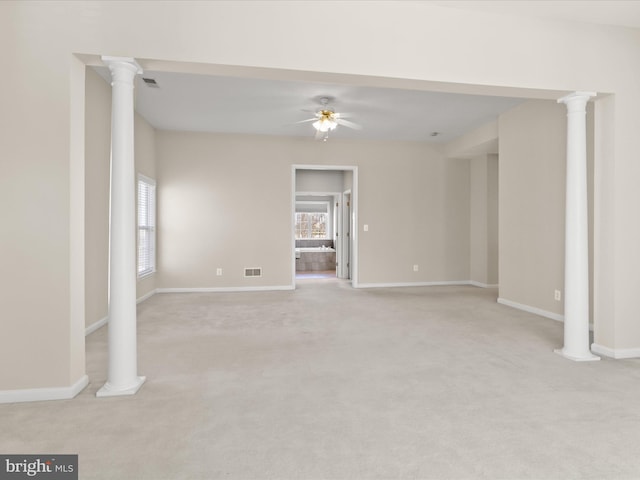 empty room with ornate columns, light colored carpet, and ceiling fan