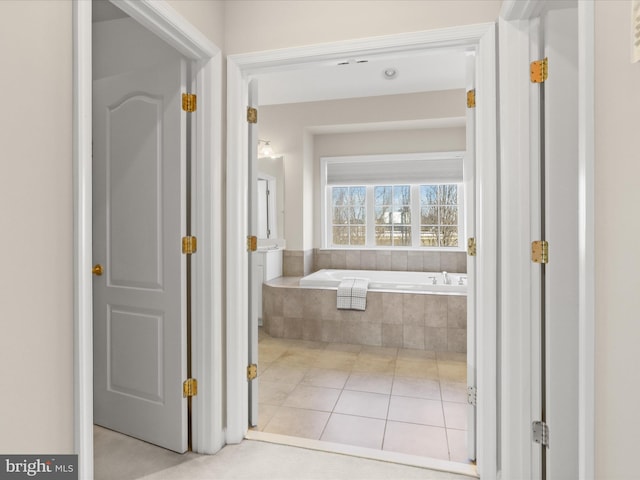 bathroom with tiled tub and tile patterned floors