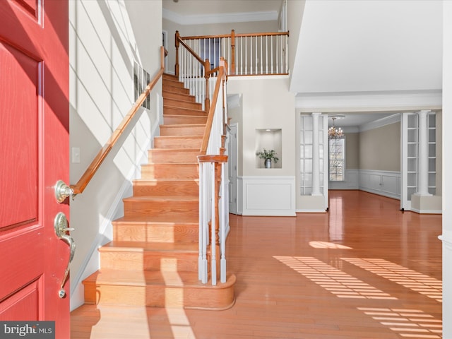 foyer with ornate columns, crown molding, hardwood / wood-style floors, and a chandelier