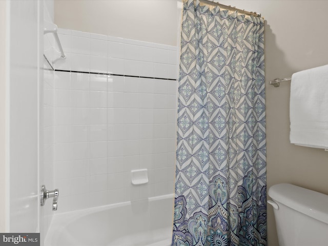 bathroom featuring shower / tub combo and toilet