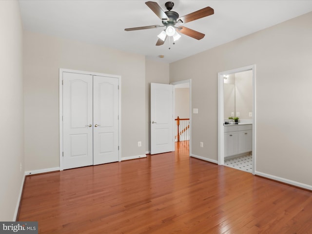 unfurnished bedroom with ceiling fan, ensuite bathroom, a closet, and light wood-type flooring