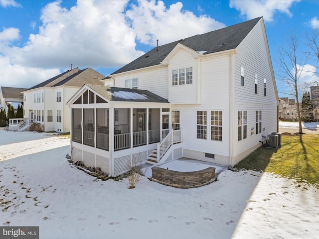 snow covered rear of property with a sunroom and central AC unit