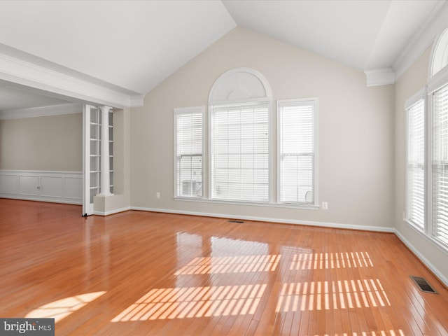 unfurnished room with lofted ceiling, crown molding, decorative columns, and light wood-type flooring