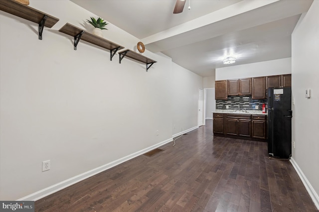 kitchen with dark brown cabinetry, sink, black fridge, dark hardwood / wood-style flooring, and decorative backsplash