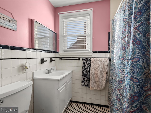 bathroom with vanity, tile walls, and toilet