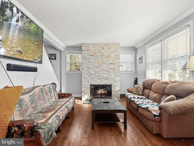 living room featuring crown molding, a stone fireplace, wood-type flooring, and plenty of natural light