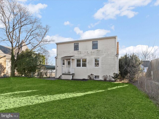 rear view of house featuring a lawn and a carport