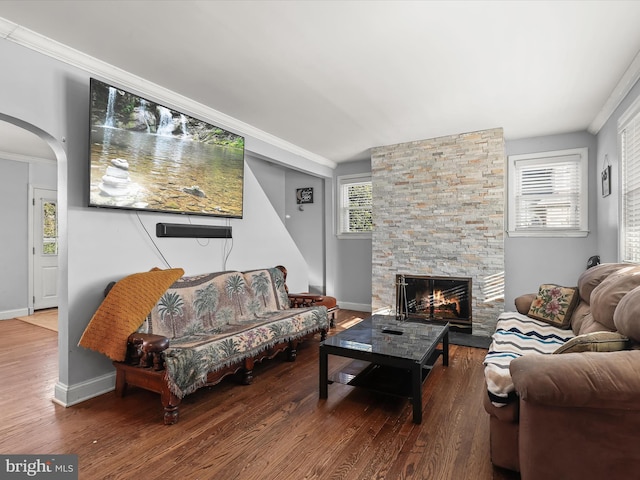 living room with a wealth of natural light, a stone fireplace, ornamental molding, and hardwood / wood-style floors