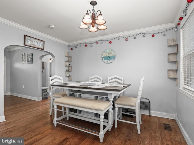 dining area with crown molding, dark hardwood / wood-style flooring, and an inviting chandelier