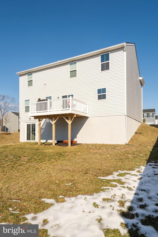 back of property featuring a wooden deck and a lawn