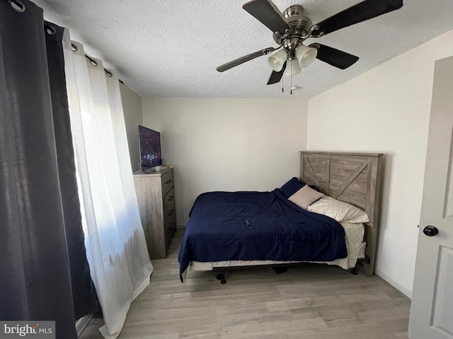 bedroom featuring light wood-type flooring, a textured ceiling, and ceiling fan