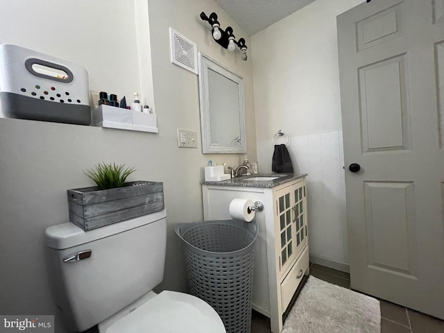 bathroom featuring toilet, tile patterned flooring, sink, and a textured ceiling