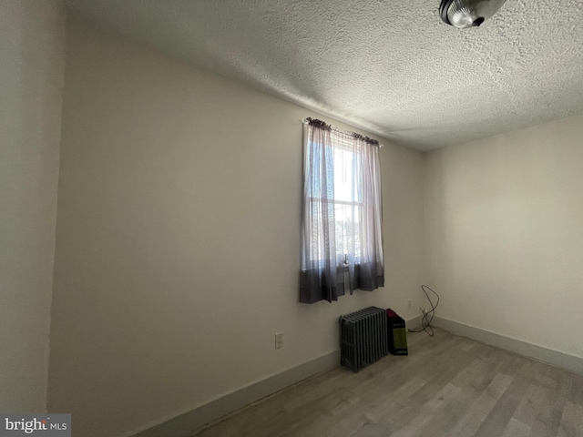 unfurnished room with light hardwood / wood-style flooring and a textured ceiling