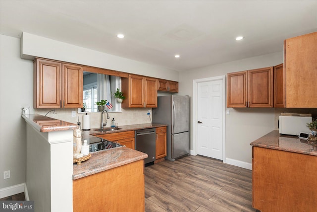 kitchen with stainless steel refrigerator, dishwasher, sink, and light stone counters