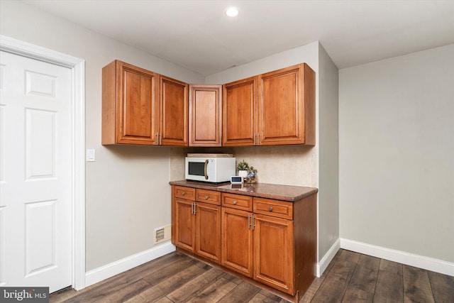 kitchen with dark stone counters and dark hardwood / wood-style floors