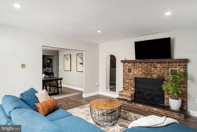 living room with dark wood-type flooring and a brick fireplace