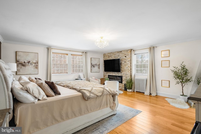 bedroom with radiator, crown molding, hardwood / wood-style floors, a notable chandelier, and a fireplace