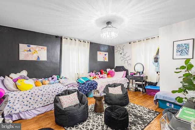 bedroom with hardwood / wood-style flooring, a notable chandelier, and multiple windows