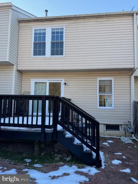 snow covered rear of property with a wooden deck