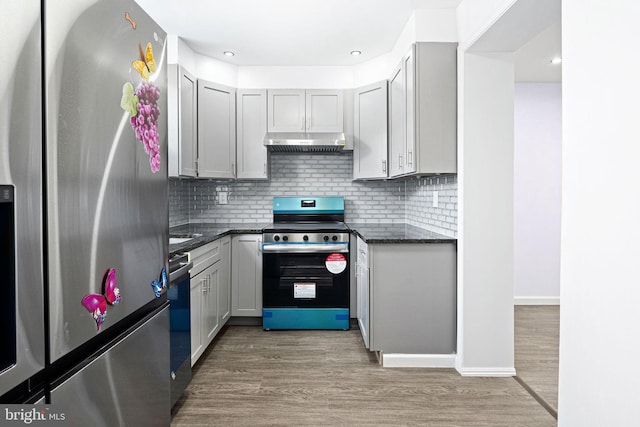 kitchen with hardwood / wood-style flooring, appliances with stainless steel finishes, decorative backsplash, and gray cabinetry