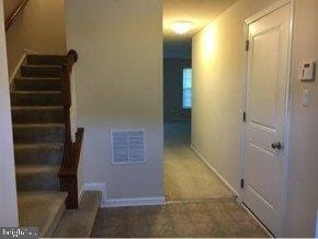 hall featuring visible vents, stairway, and baseboards