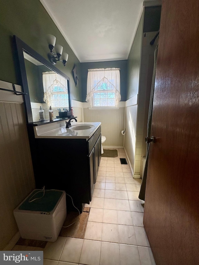 bathroom with tile patterned flooring, vanity, wood walls, and toilet