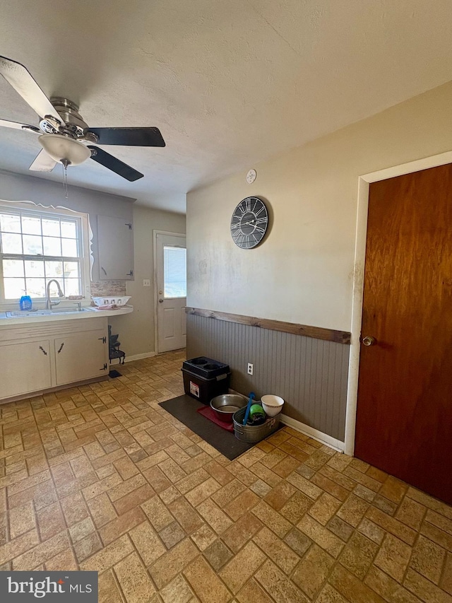 kitchen featuring white cabinetry, ceiling fan, sink, and a textured ceiling