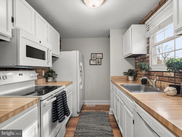 kitchen featuring white cabinetry, sink, hardwood / wood-style floors, and white appliances