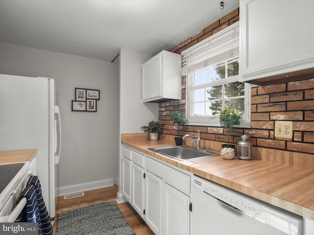 kitchen with sink, white appliances, white cabinetry, backsplash, and wood-type flooring