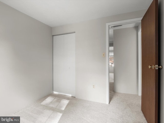 unfurnished bedroom featuring a closet and light carpet