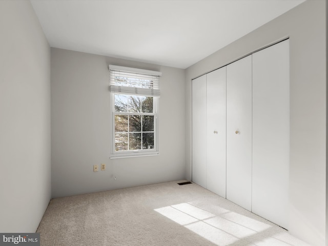 unfurnished bedroom with light carpet and a closet