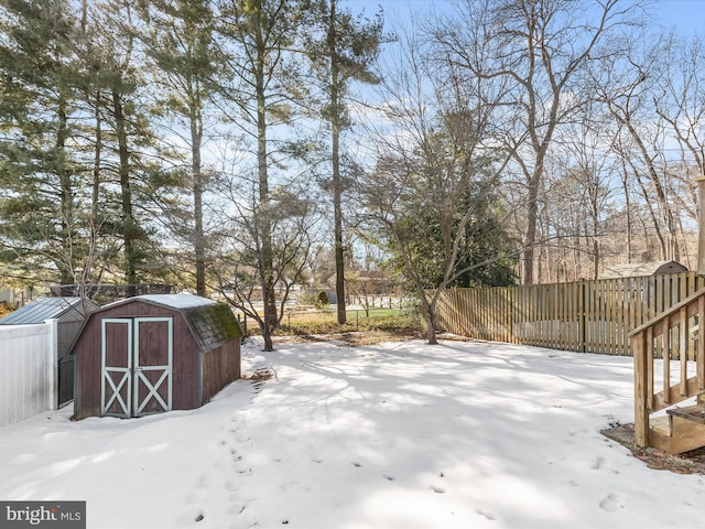 yard layered in snow featuring a storage shed