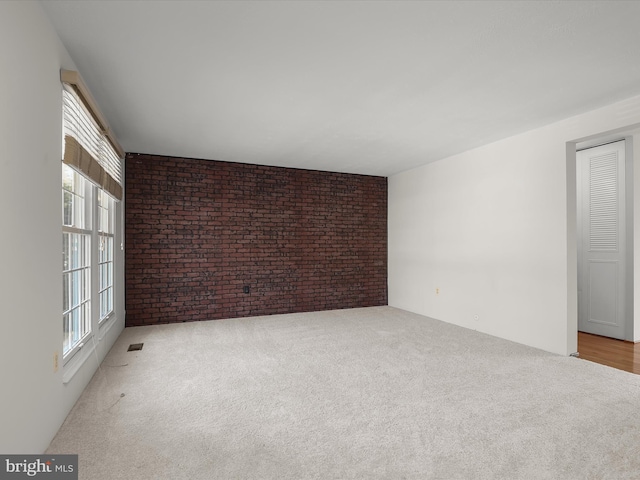 carpeted spare room with brick wall