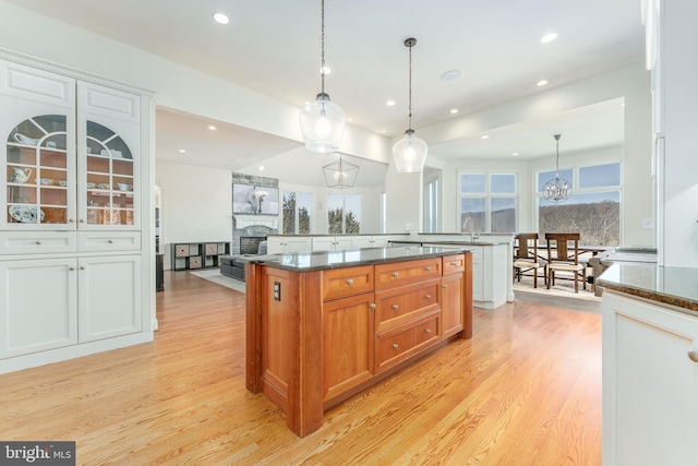 kitchen with hanging light fixtures, light wood-style flooring, plenty of natural light, and a fireplace