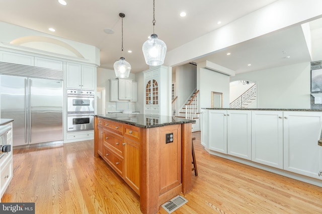 kitchen with dark stone countertops, light wood-style floors, visible vents, and appliances with stainless steel finishes