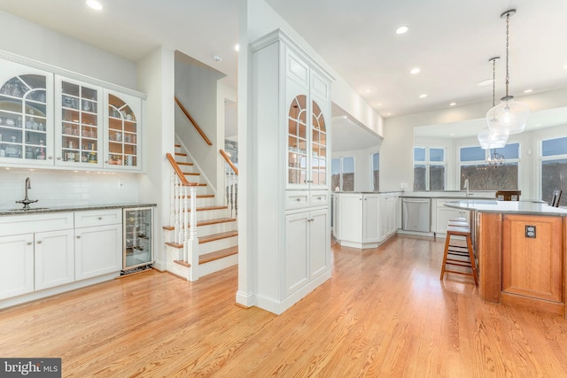 kitchen with beverage cooler, light wood-style flooring, dishwasher, and a sink