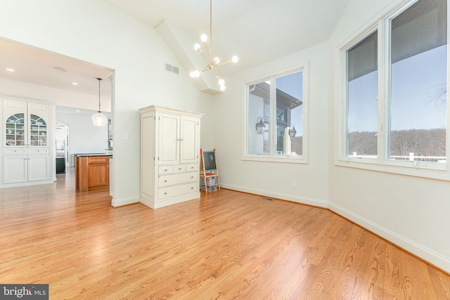 unfurnished room with light wood-type flooring, visible vents, baseboards, an inviting chandelier, and lofted ceiling