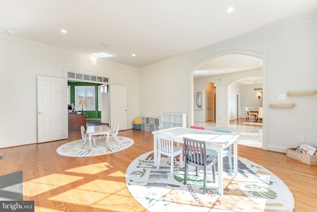 dining space with crown molding, recessed lighting, wood finished floors, and arched walkways