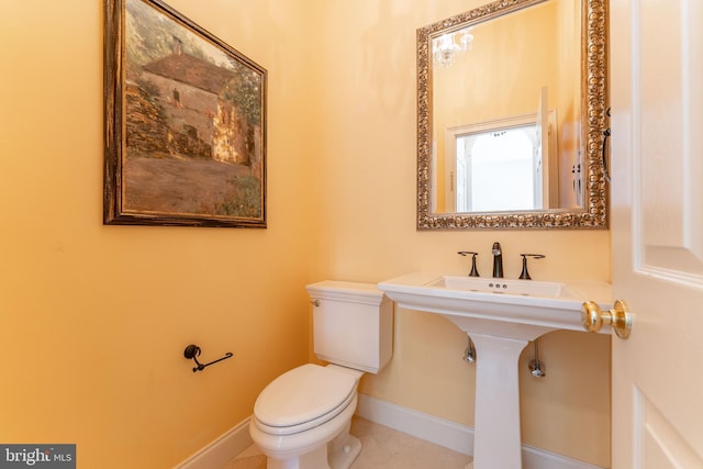 half bathroom featuring tile patterned flooring, toilet, and baseboards