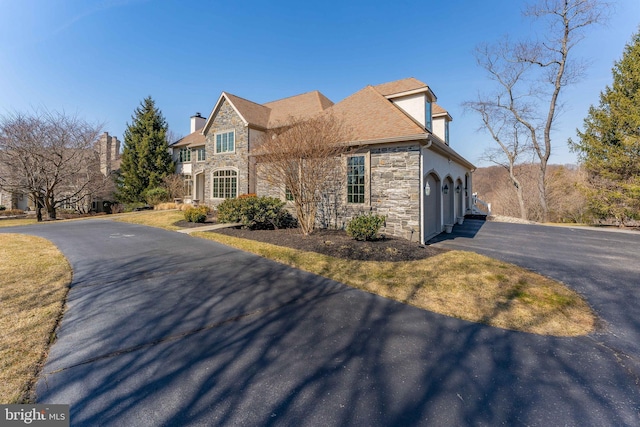 view of front of property with a garage, stone siding, and driveway